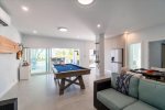 Indoor/outdoor entertainment room with pool table, dominos table, and TV.